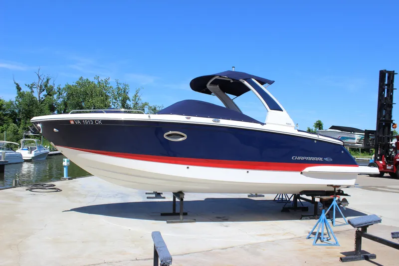 Slide: The Image of 2020 Chaparral 277 SSX boat on dry dock, blue and white with red stripe, sunny day. - 2