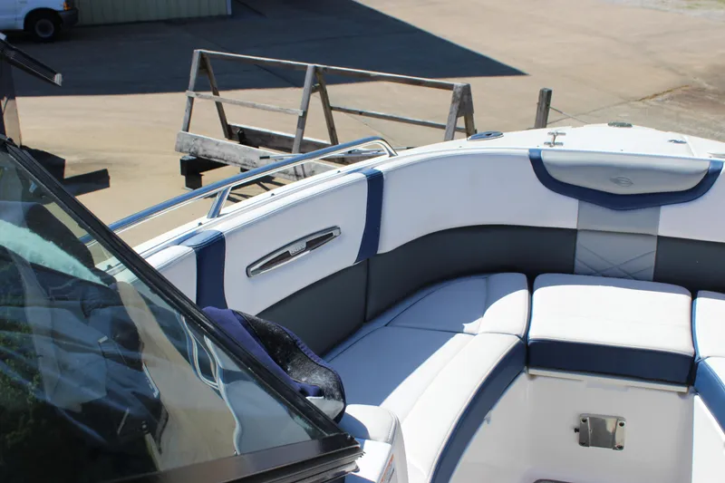 Slide: The Image of 2020 Chaparral 277 SSX boat interior with white and blue seating, docked outdoors. - 24