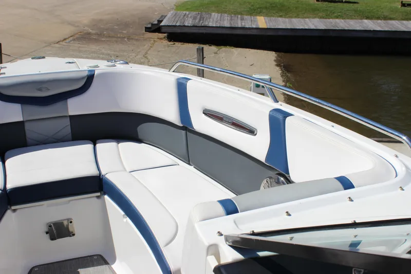 Slide: The Image of 2020 Chaparral 277 SSX boat interior with white and blue seating near a dock. - 25
