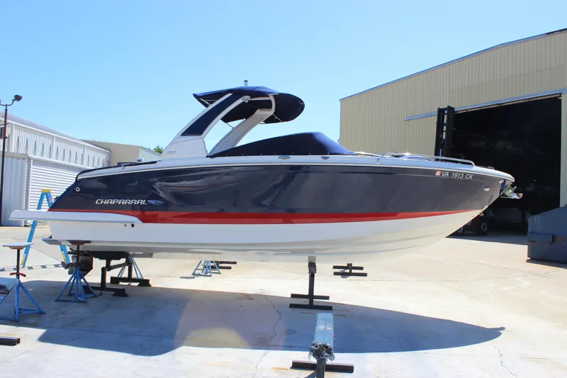 Slide: The Image of 2020 Chaparral 277 SSX boat on stands, blue and white hull, outdoor setting. - 5