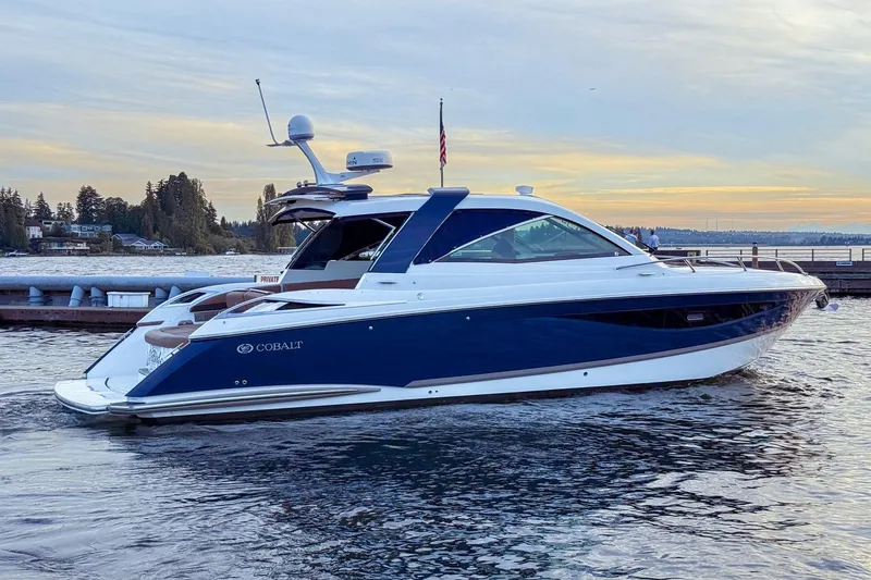 Slide: The Image of 2017 Cobalt A40 Coupe yacht on serene water at sunset, docked near a pier. - 11