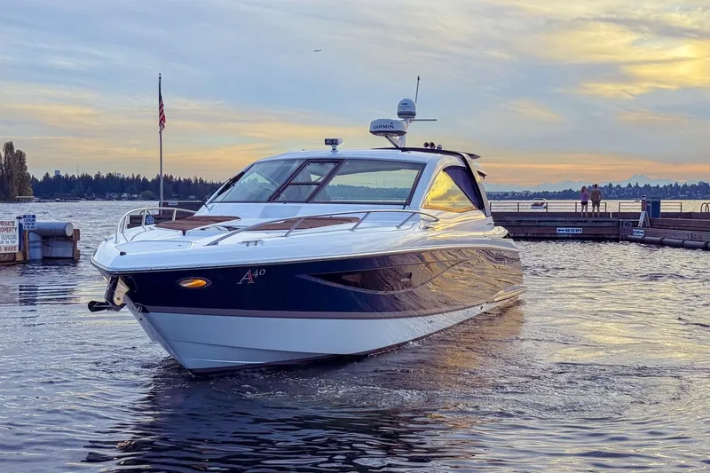 Slide: The Image of 2017 Cobalt A40 Coupe boat on water at sunset, near a dock with flag. - 22