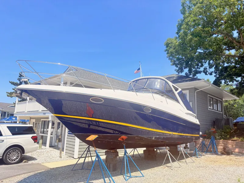 Slide: The Image of A 2009 Regal Commodore 3760 IO is on stands in a yard. It features a blue hull and white deck. - 3