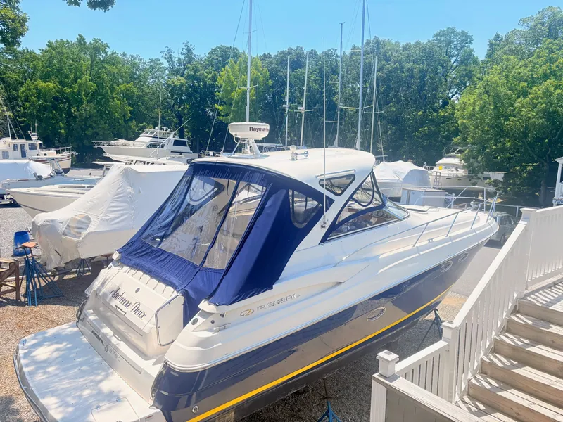 Slide: The Image of A 2009 Regal Commodore 3760 IO is on a boatyard. It features a blue canopy. - 4