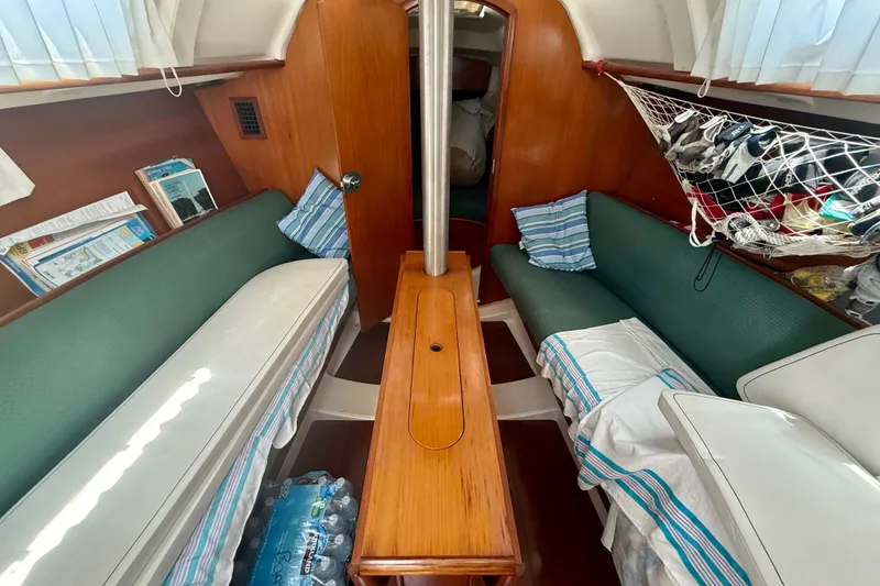 Slide: The Image of Interior of 2002 Beneteau Oceanis Clipper 311 sailboat with green seating and wooden table. - 10