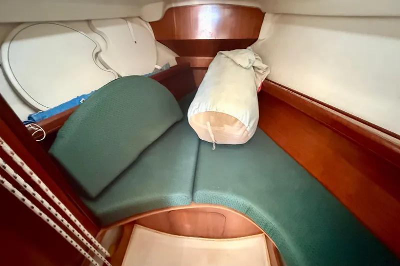 Slide: The Image of Interior cabin of 2002 Beneteau Oceanis Clipper 311 with green cushions and wooden finish. - 11