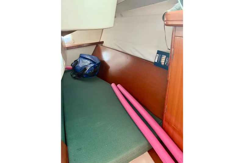 Slide: The Image of Interior cabin of 2002 Beneteau Oceanis Clipper 311 with green cushion and pink pool noodles. - 19