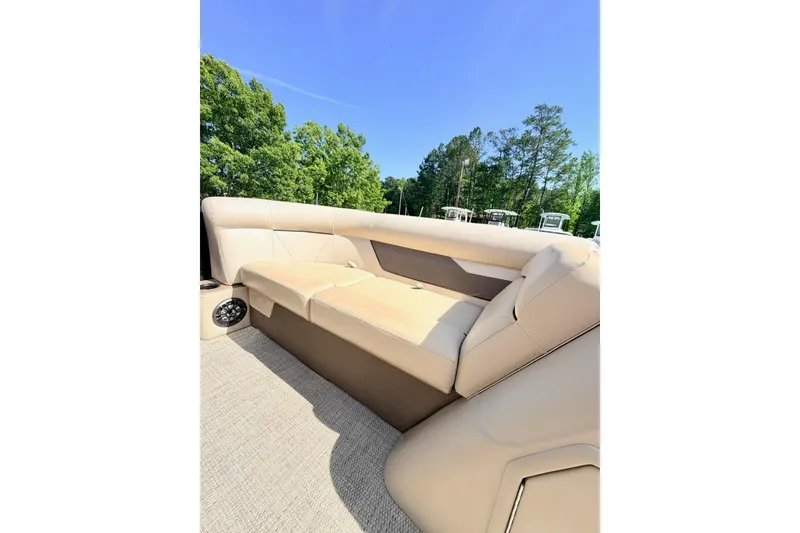Slide: The Image of 2021 Crest Classic DLX 220 SLC boat interior with beige seating under clear blue sky. - 11