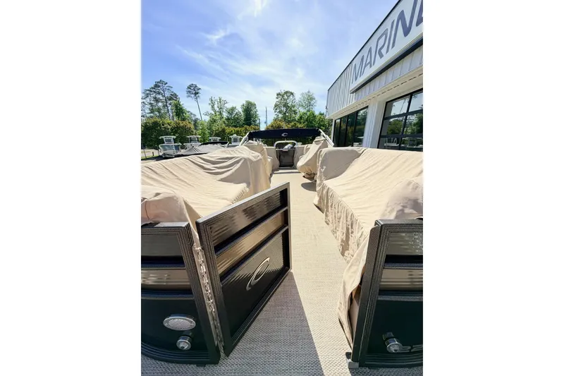 Slide: The Image of 2021 Crest Classic DLX 220 SLC pontoon boat with protective covers, parked outdoors. - 4