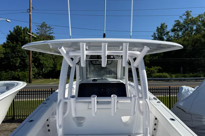 Slide: The Image of 2026 Sportsman Open 302 Center Console boat with rod holders and T-top, parked outdoors. - 15