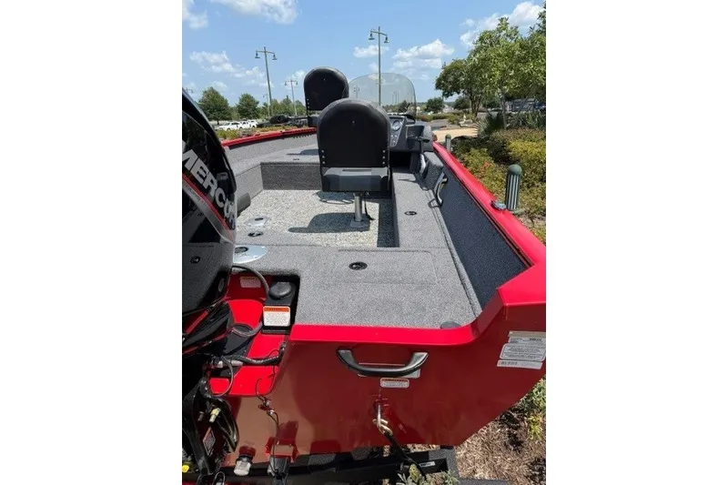 Slide: The Image of Red 2026 Tracker Pro Guide V-16 SC boat with seating and motor, parked outdoors. - 6