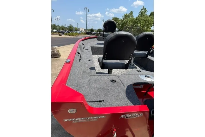 Slide: The Image of 2026 Tracker Pro Guide V-16 SC boat with red exterior and seating, parked outdoors. - 5