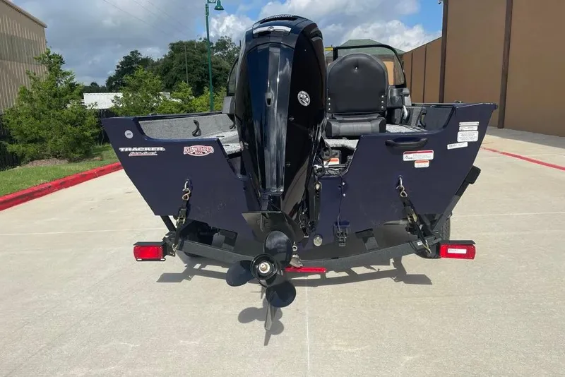 Slide: The Image of 2026 Tracker Pro Guide V-16 WT boat, rear view with motor, parked outdoors. - 3