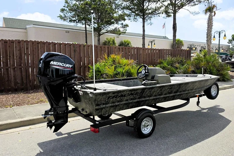 Slide: The Image of 2026 Tracker Grizzly 1648 SC boat with Mercury engine on trailer, parked outdoors. - 2