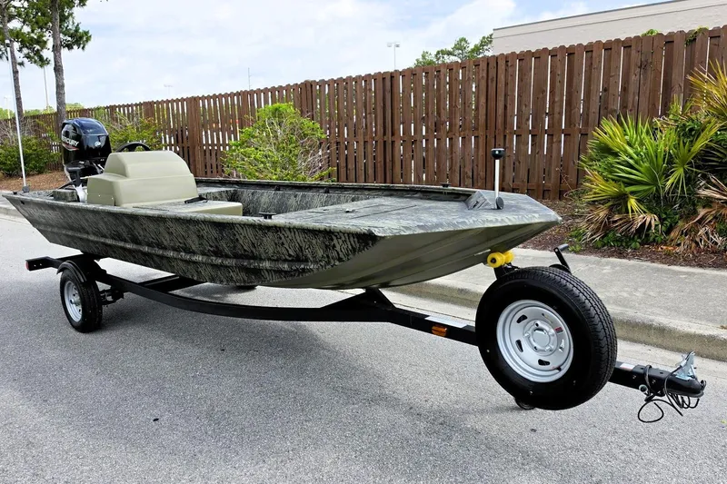 Slide: The Image of 2026 Tracker Grizzly 1648 SC boat on trailer, parked on street, with camouflage design. - 4