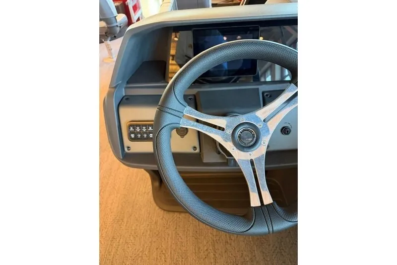 Slide: The Image of Steering wheel of 2026 Sun Tracker Fishin' Barge 22 DLX boat, featuring control panel. - 13