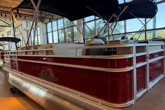 Slide: The Image of 2026 Sun Tracker Fishin' Barge 22 DLX pontoon boat displayed indoors, featuring a sleek red design. - 2