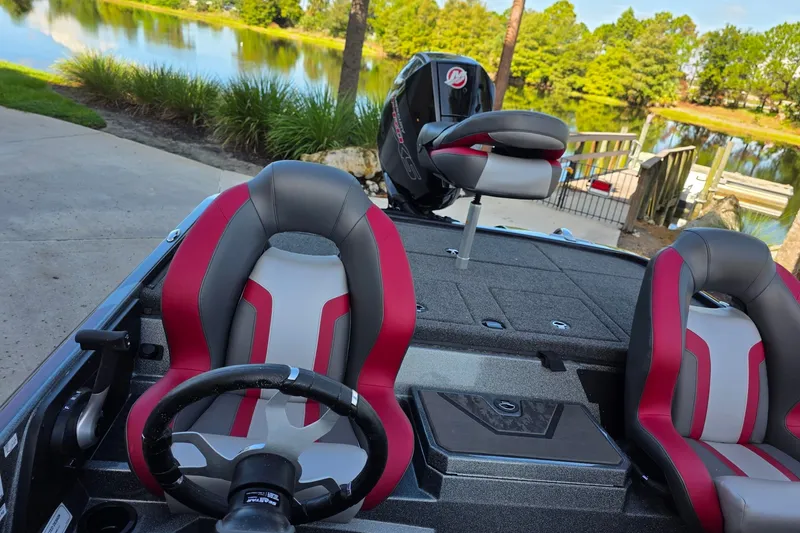 Slide: The Image of 2026 Nitro Z20 XL boat interior with red and gray seats by a scenic lake. - 7
