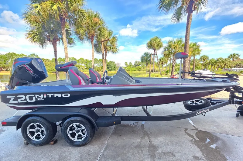 The Image of 2026 Nitro Z20 XL boat on trailer, parked near palm trees under a clear blue sky. - 0