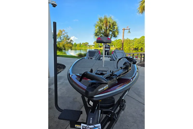 Slide: The Image of 2026 Nitro Z20 XL boat with Minn Kota motor, parked near a scenic lake. - 2