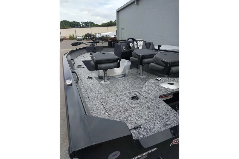 Slide: The Image of 2026 Tracker Pro Guide V-16 SC boat with seating and steering console, parked outdoors. - 6