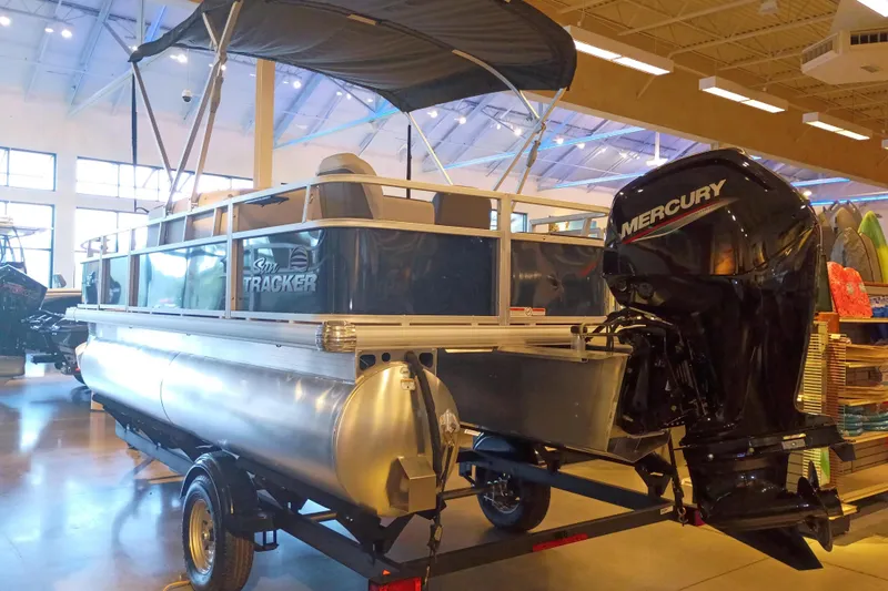 Slide: The Image of 2026 Sun Tracker Bass Buggy 18 DLX pontoon boat with Mercury outboard motor in showroom. - 1