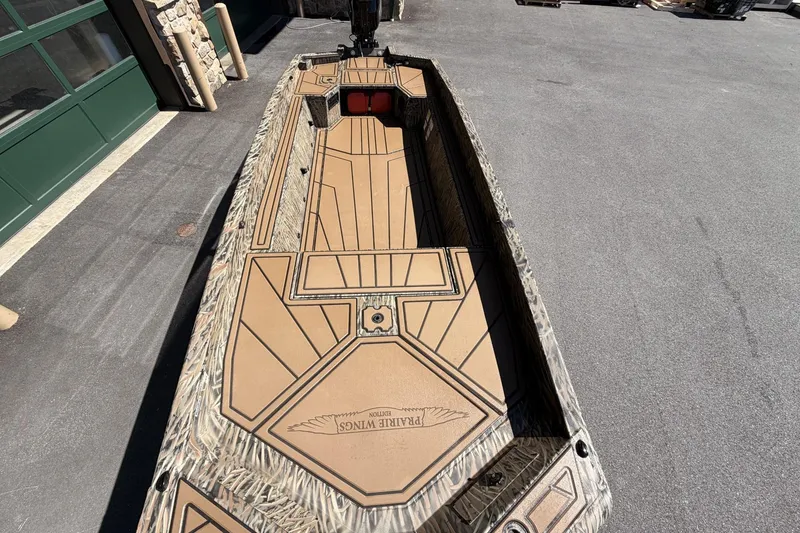 Slide: The Image of 2026 Tracker Grizzly 1650 T Prairie Wings Edition boat with camouflage design on pavement. - 3