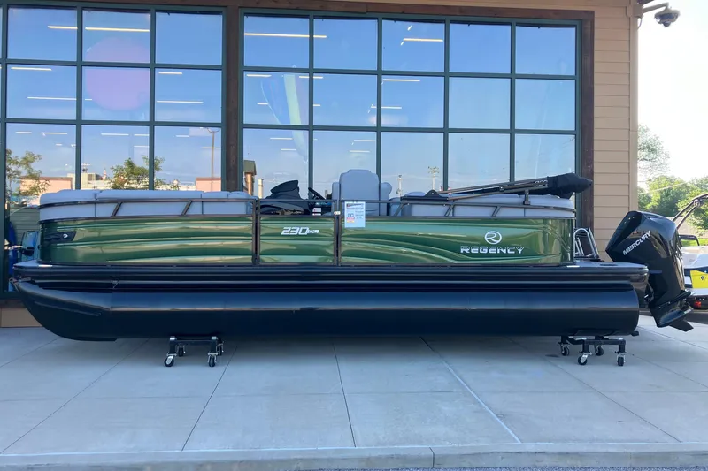 Slide: The Image of 2026 Regency 230 DL pontoon boat displayed outside a showroom. - 1
