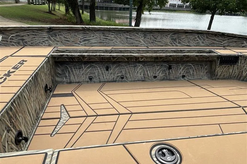 Slide: The Image of 2026 Tracker Grizzly 1756 T Marsh boat interior with camo design near a lake. - 9