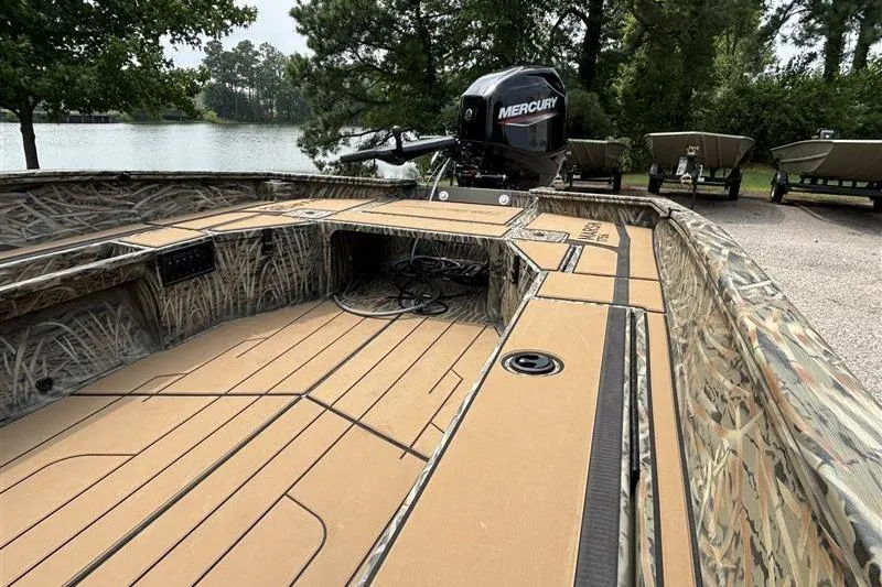 Slide: The Image of 2026 Tracker Grizzly 1756 T Marsh boat with Mercury engine, docked near a serene lake. - 14