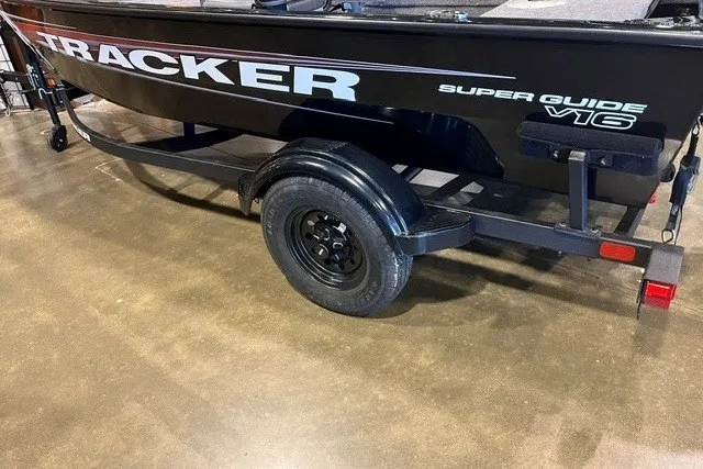 The Image of 2026 Tracker Super Guide V-16 SC boat on trailer, black exterior, indoor setting. - 0