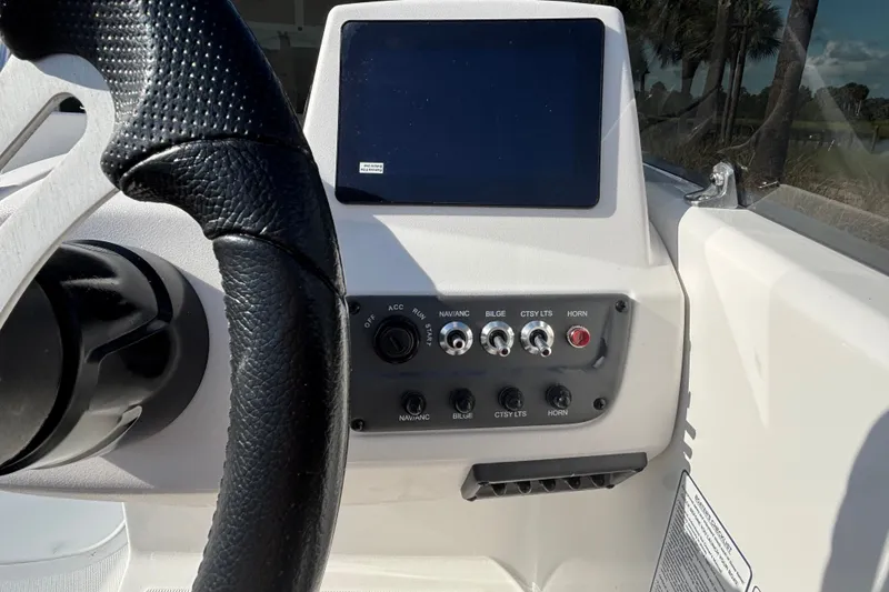 Slide: The Image of Steering wheel and control panel of 2026 Tahoe T18 boat, featuring switches and display. - 11