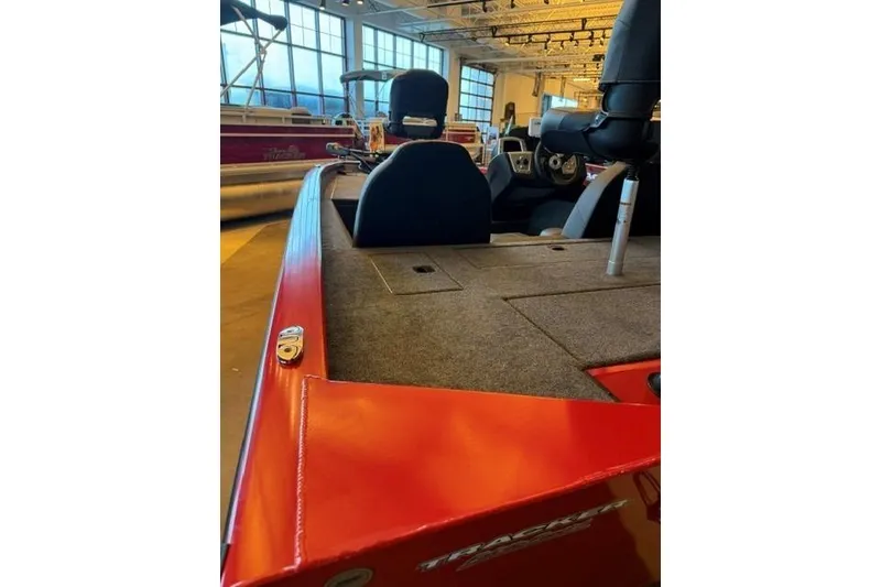 Slide: The Image of 2026 Tracker Pro Team 175 boat interior with red exterior and seating in showroom. - 6