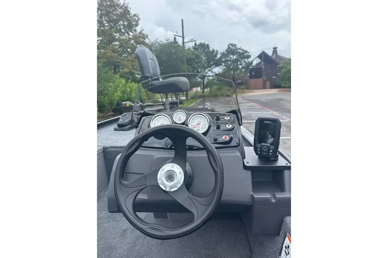 Slide: The Image of 2026 Tracker Pro 170 boat dashboard with steering wheel and gauges, parked outdoors. - 7