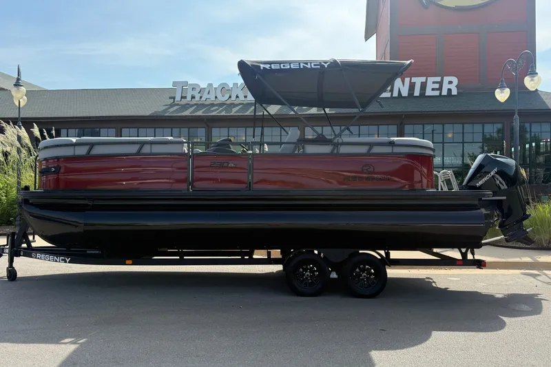 The Image of 2026 Regency 230 DL pontoon boat on trailer, parked outside a building. - 0