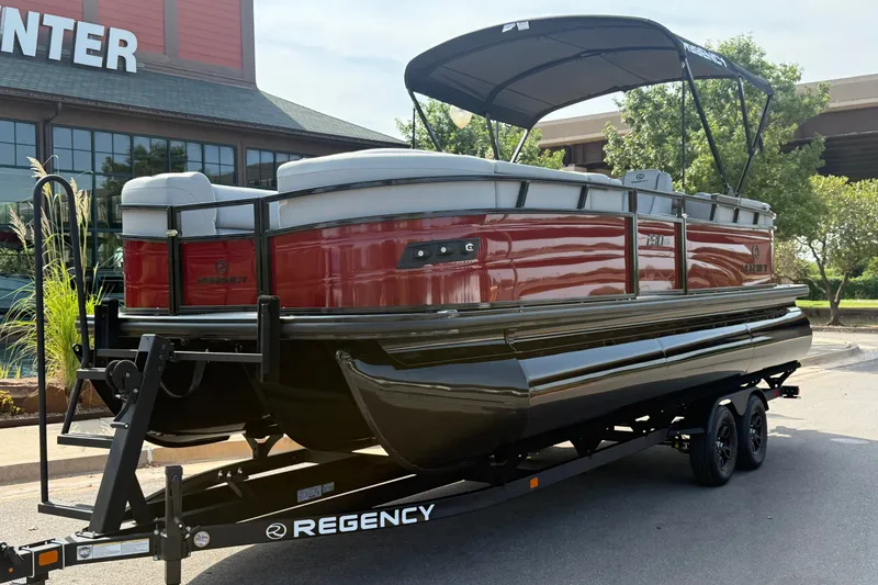 Slide: The Image of 2026 Regency 230 DL pontoon boat on trailer, parked outside a building. - 1
