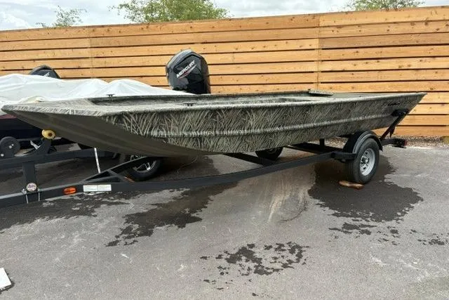 Slide: The Image of 2026 Tracker Grizzly 1754 Utility boat on trailer, camo design, parked outdoors. - 19