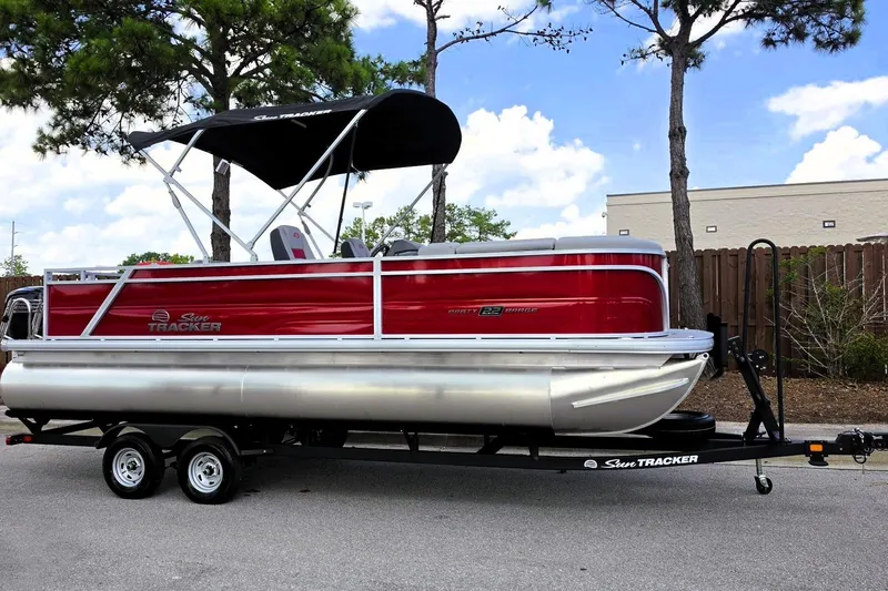 Slide: The Image of 2026 Sun Tracker Party Barge 22 RF DLX pontoon boat on trailer, parked outdoors. - 5