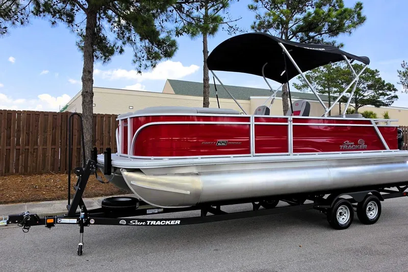 Slide: The Image of 2026 Sun Tracker Party Barge 22 RF DLX pontoon boat on trailer, parked outdoors. - 10