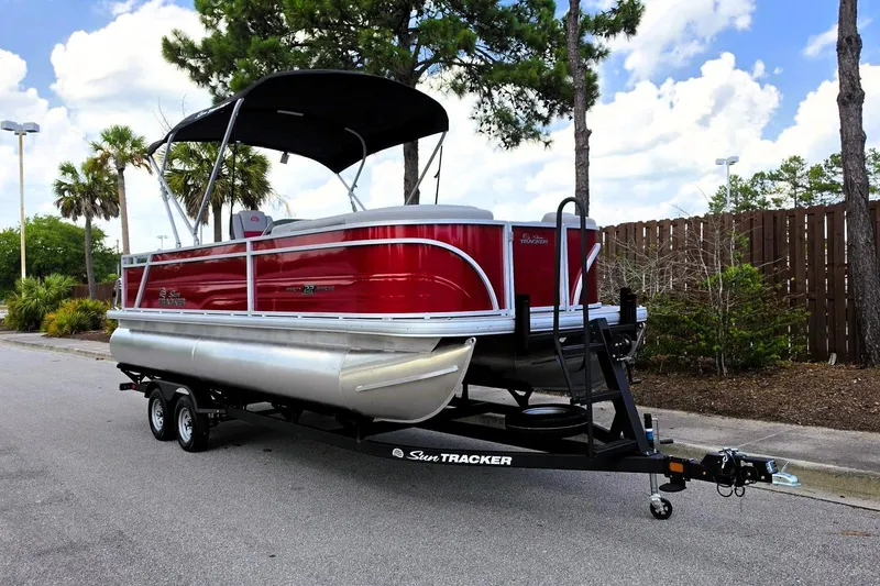 Slide: The Image of 2026 Sun Tracker Party Barge 22 RF DLX pontoon boat on trailer, parked outdoors. - 6