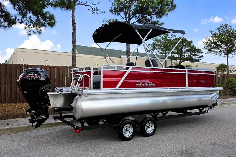 Slide: The Image of 2026 Sun Tracker Party Barge 22 RF DLX pontoon boat on trailer, parked outdoors. - 2