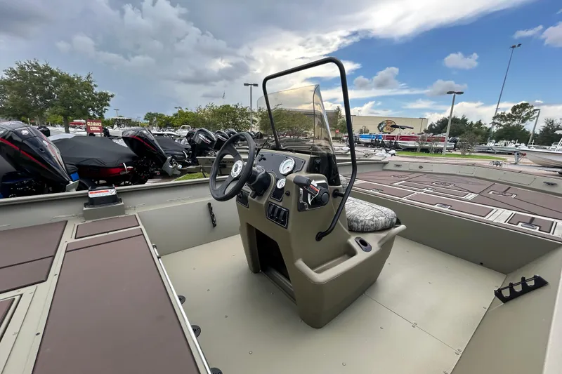 Slide: The Image of 2026 Tracker Grizzly 2072 CC boat interior with steering console, parked outdoors under cloudy sky. - 8
