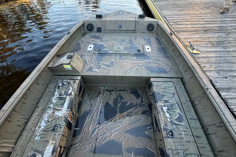 Slide: The Image of 2019 SeaArk Predator 220 AK SC boat with camouflage design docked by the water. - 13