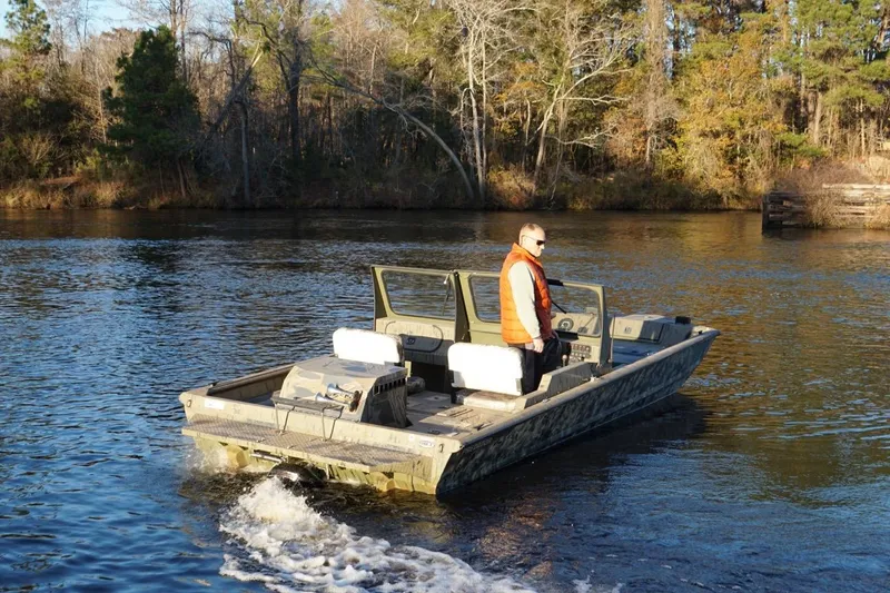 Slide: The Image of 2019 SeaArk Predator 220 AK SC boat on a calm river with a person onboard. - 6