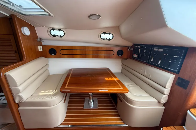 Slide: The Image of 2001 Pursuit 3400 Express cabin with wood table, beige seating, and control panels. - 22