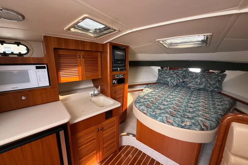 Slide: The Image of 2001 Pursuit 3400 Express cabin interior with bed, kitchenette, and wood cabinetry. - 24