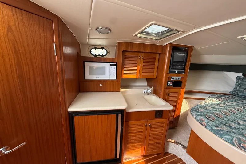 Slide: The Image of 2001 Pursuit 3400 Express cabin interior with kitchenette, microwave, and cozy sleeping area. - 25