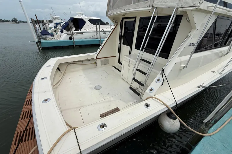 Slide: The Image of 1989 Viking 41 Convertible yacht docked, showcasing spacious deck and sleek design. - 5