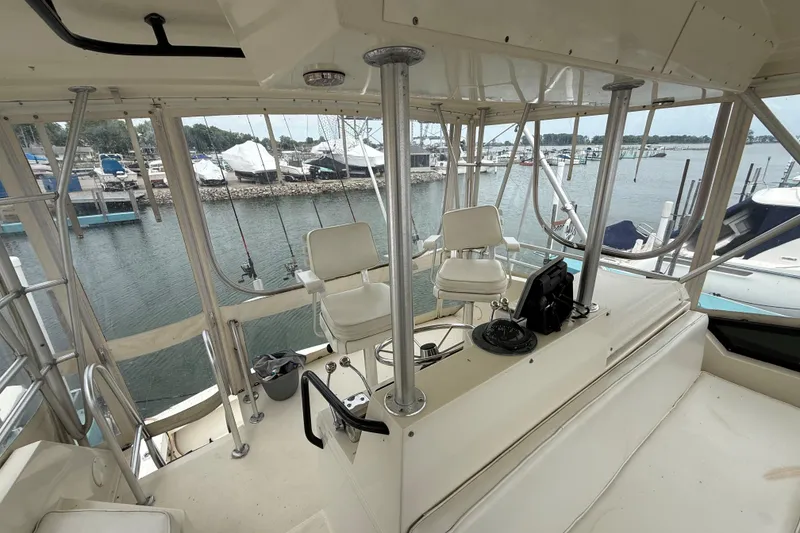 Slide: The Image of 1989 Viking 41 Convertible yacht helm with marina view, featuring dual captain chairs and navigation equipment. - 8