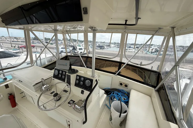 Slide: The Image of 1989 Viking 41 Convertible boat cockpit with steering wheel, Garmin navigation, and marina view. - 7